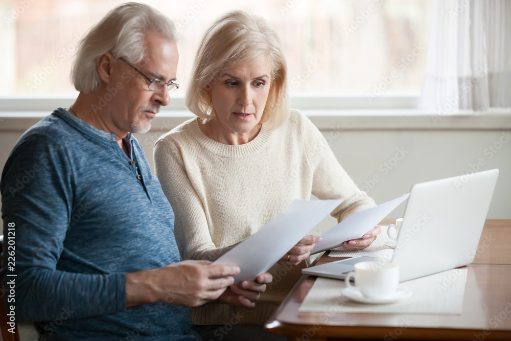 Serious worried senior couple calculating bills to pay or checking domestic finances stressed of debt, retired elderly old family reading documents concerned about loan bankruptcy money problems Serious worried senior couple calculating bills to pay or checking domestic finances stressed of debt, retired elderly old family reading documents concerned about loan bankruptcy money problems