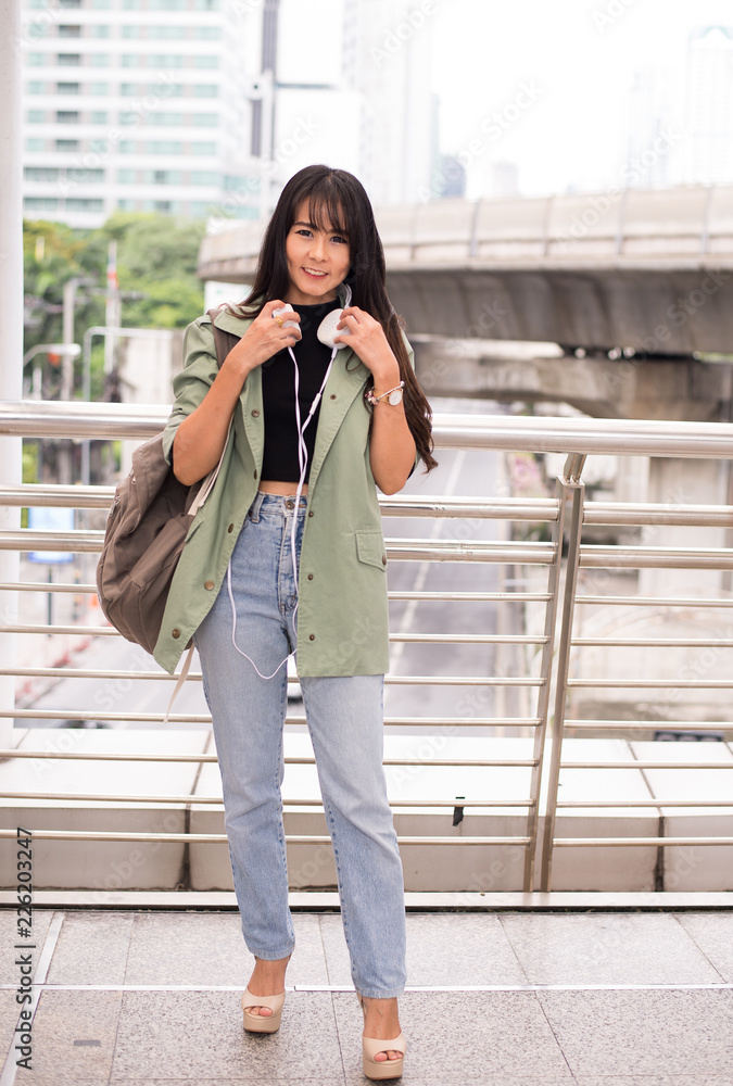 Fototapeta premium Beautiful young teen using headphones and listening to music at shopping center