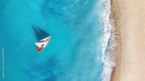 Yacht on the water surface from top view. Turquoise water background from top view. Summer seascape from air. Travel concept and idea