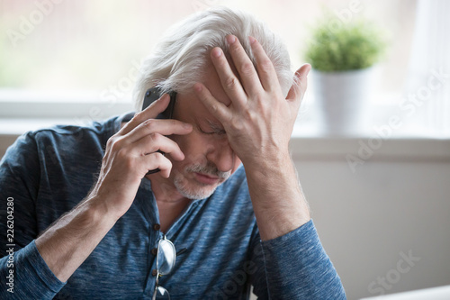 Frustrated older mature retired man feeling upset desperate talking on the phone having problems debt, stressed sad middle aged male depressed by hearing bad news during mobile conversation at home © fizkes