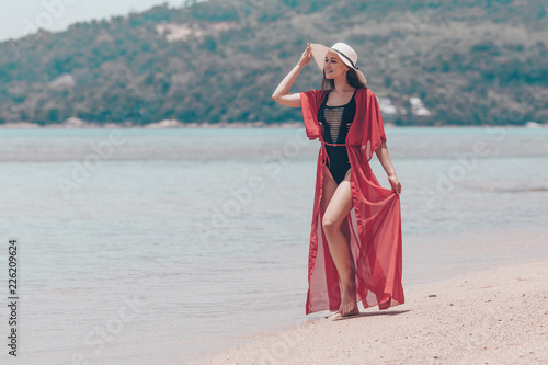 Sexy and Beautiful Young Woman in red Cape Relaxing Tropical Island. Walking on White Sandy Beach. Vacation Travel Concept.
