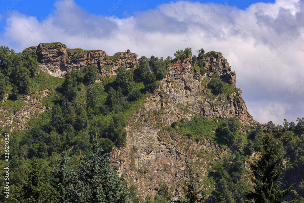 Stone ledge of a rocky ridge against the blue sky. Caucasian mountain range in Russia.