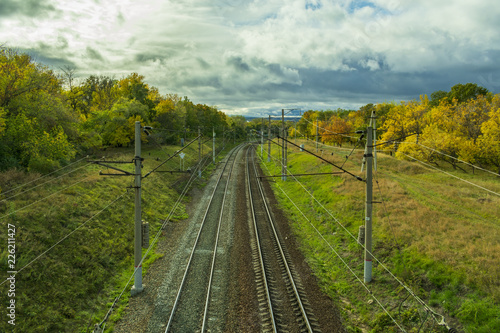 paths of the turning railway in the autumn, among the yellowing trees and the autumn cloudy sky