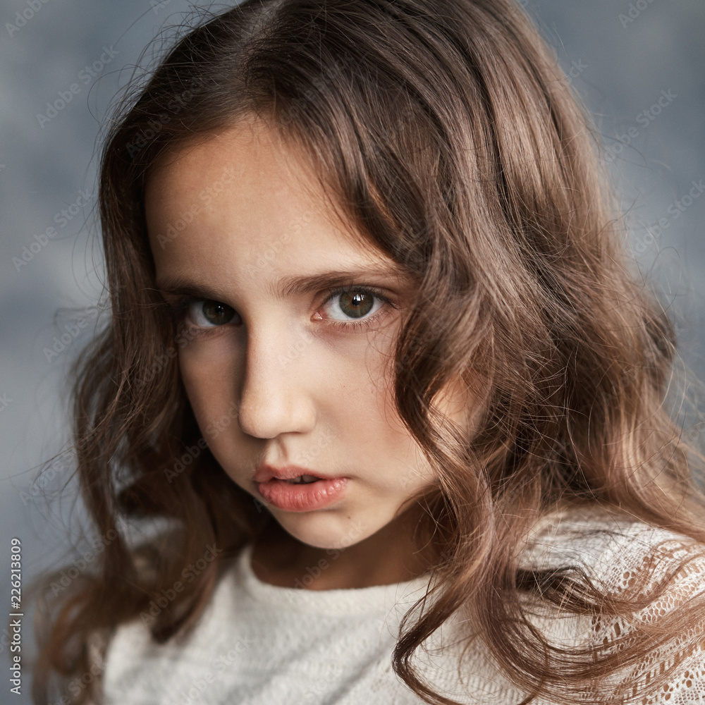 Close up portrait of serious young caucasian girl with curly hair and perfect healthy skin. Teen age girl looking at camera with sadness. Close up portrait of serious young caucasian girl with curly hair and perfect healthy skin. Teen age girl looking at camera with sadness.