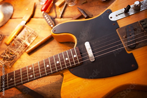 Guitar on repair desk. Vintage electric guitar on a repair work shop. Single cutaway electric guitar, amber color.