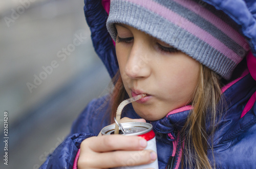 girl drinking a drink through a straw from a can