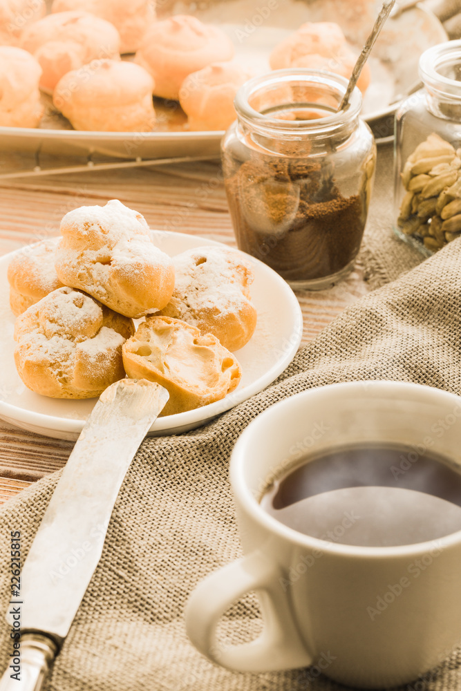 Cup of black tea with home made profiteroles on a rustic wooden table. Cup of black tea with home made profiteroles on a rustic wooden table.