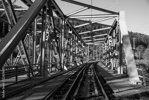 Steel railroad bridge close up on a bright autumn day in black and white.