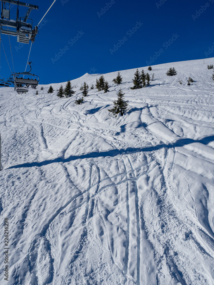 Ski lift and ski slope with skiers under it on sunny winter day with blue sky. Alpine resort Courchevel, France. January, 2018 Ski lift and ski slope with skiers under it on sunny winter day with blue sky. Alpine resort Courchevel, France. January, 2018