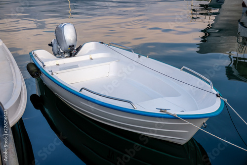 Blue white power boat stops at the port  Small motor boat on a calm , silent sea Reflections  Motorized boat and sea at sunset