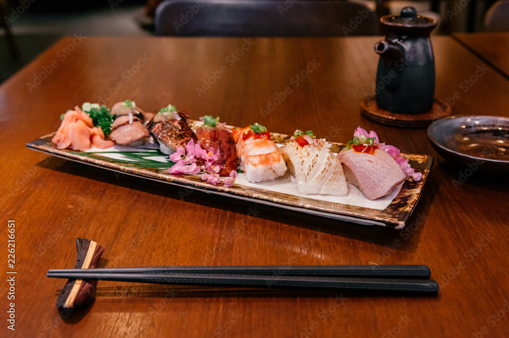 Many kinds of Japanese Sushi on ceramic plate on wood table in restaurant