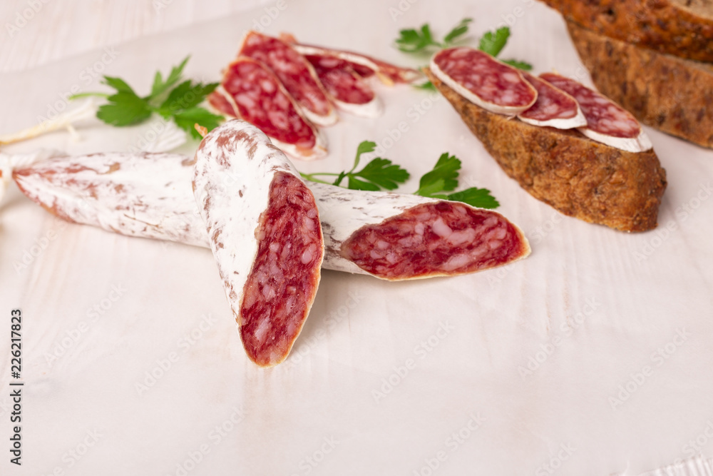 Salami and bread on white wooden background. Top view. Copy space Salami and bread on white wooden background. Top view. Copy space