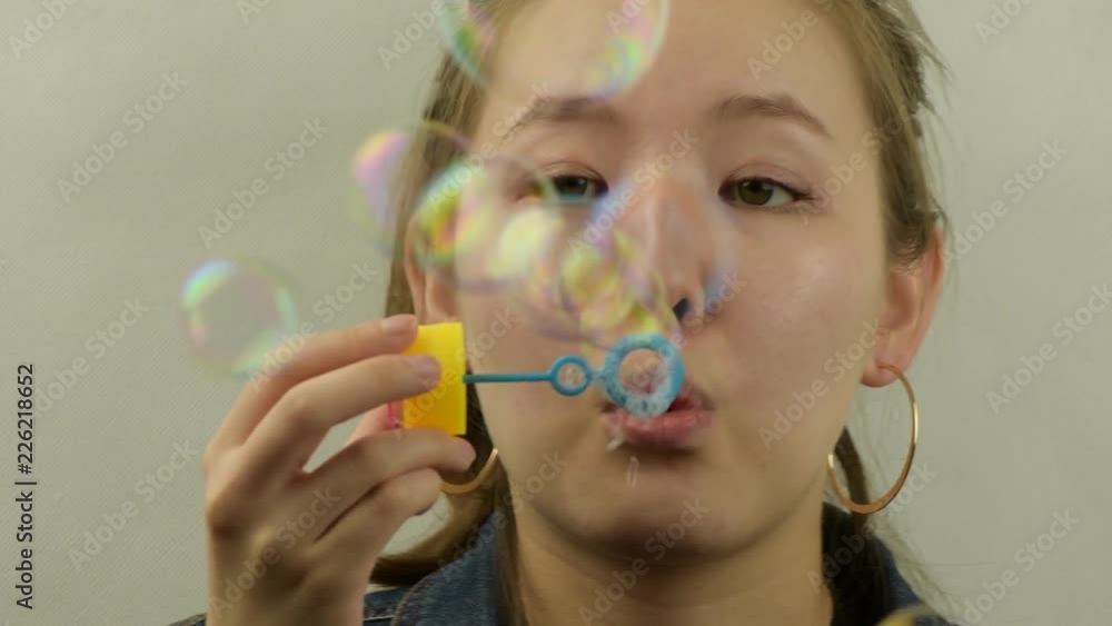 Asian young girl playing with a bubble blower. Asian young girl playing with a bubble blower.