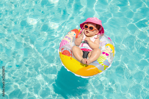 Cute Baby Girl In Sunglasses Floating On Tropical Blue Water