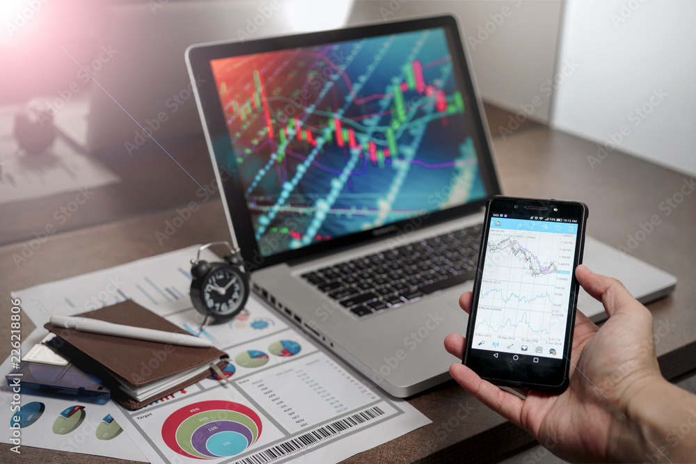 A Computer Tablet and ultra-slim smartphone with candle stick chart on the screen a business and finance conceptual A Computer Tablet and ultra-slim smartphone with candle stick chart on the screen a business and finance conceptual