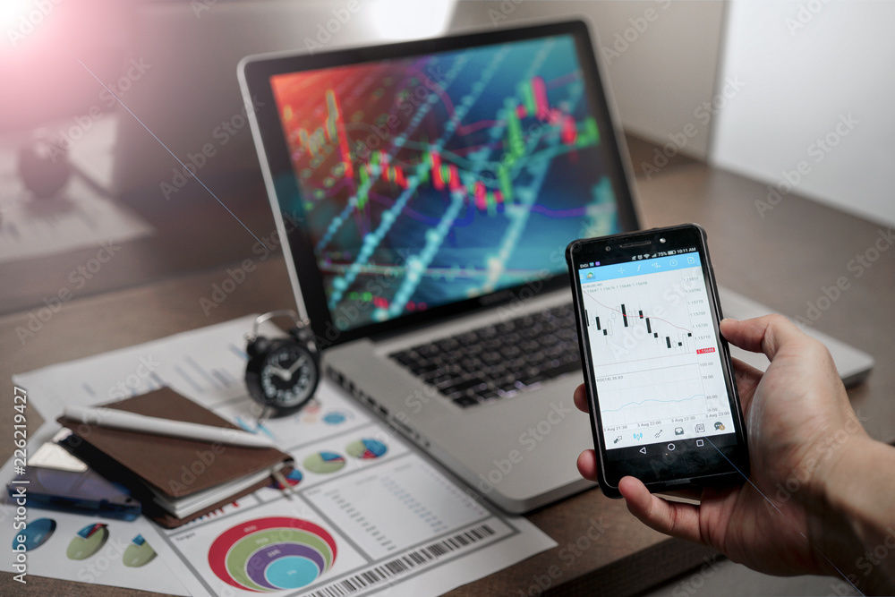 A Computer Tablet and ultra-slim smartphone with candle stick chart on the screen a business and finance conceptual A Computer Tablet and ultra-slim smartphone with candle stick chart on the screen a business and finance conceptual