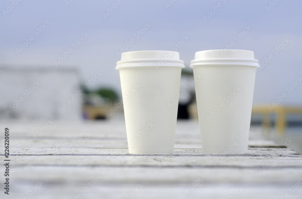 Two paper coffee cups on a wooden table by the seaside Two paper coffee cups on a wooden table by the seaside