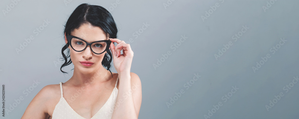 Young woman with eye glasses on a gray background Young woman with eye glasses on a gray background