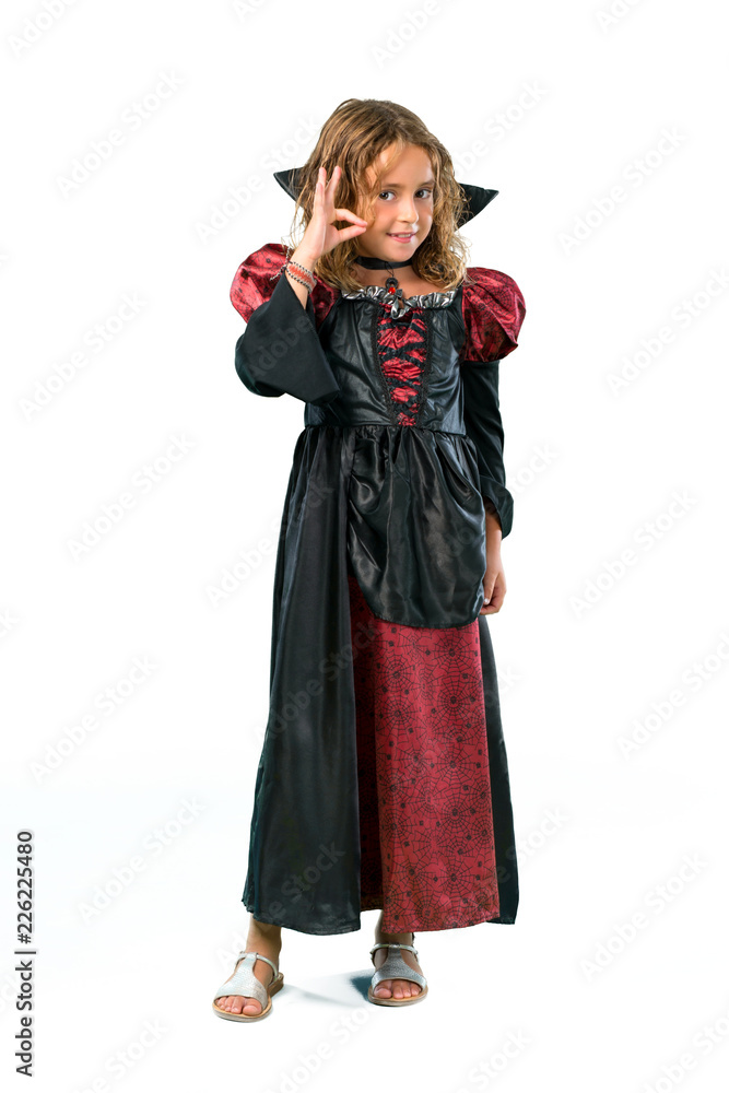 A full-length shot of a Kid dressed as a vampire at halloween holidays showing an ok sign with fingers isolated on white