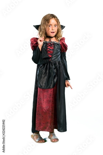 A full-length shot of a Kid dressed as a vampire at halloween holidays standing and thinking an idea isolated on white