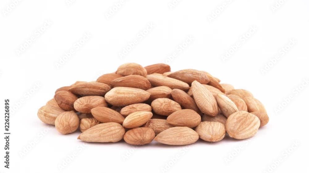 A pile of apricot kernels heap. Smoothly rotating on the turntable, isolated on the white background. Close-up. Macro. A pile of apricot kernels heap. Smoothly rotating on the turntable, isolated on the white background. Close-up. Macro.