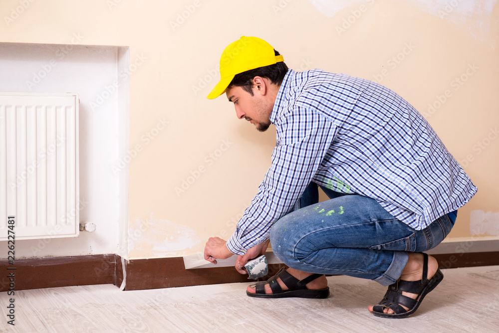 Young contractor sanding wall down with sandpaper 