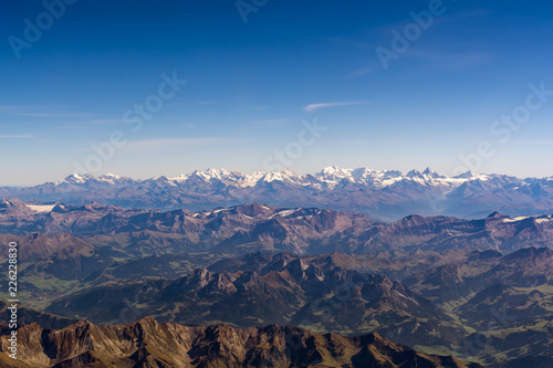 Panoramic view of the Swiss Alps from a plane at high altitude on a bright sunny day.