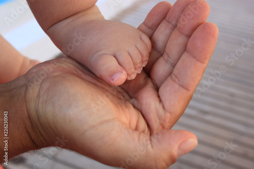 childs feet into the father’s hand, father’s day, small baby feet in the hands of man, appreciation of father, family care, support of dad