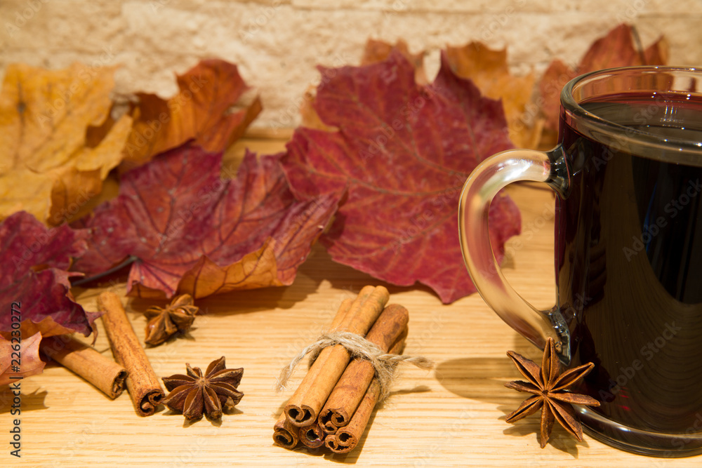 Red mulled wine with orange, cinnamon rolls, cloves, walnuts and anise stars. Brick wall background.