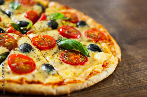 sliced Pizza Margherita or Margarita with Mozzarella cheese  tomato  olive. Italian pizza on wooden background