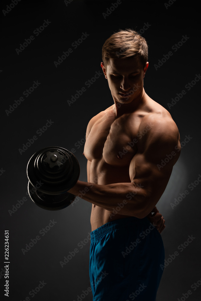 Strong bodybuilder with perfect deltoid muscles, shoulders, biceps, triceps and chest. Close up power fitness man. Handsome power athletic man in training swap muscles with dumbbells. Black background Strong bodybuilder with perfect deltoid muscles, shoulders, biceps, triceps and chest. Close up power fitness man. Handsome power athletic man in training swap muscles with dumbbells. Black background