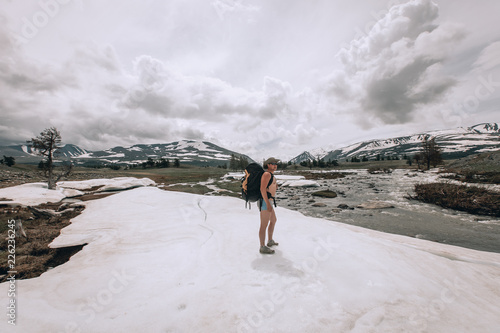 Fotografija naked tourist in shorts with a backpack goes to the mountains