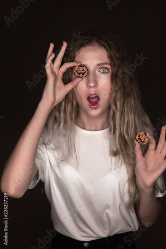 Shocked surprised excited woman posing isolated over dark beige background wall holding pumpkin halloween glitter decor in hands.