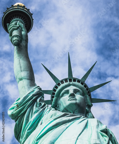Estatua de la libertad, vista desde un ángulo bajo, con fondo nublado y cielo azul, en la Isla de la Libertad de Nueva York, EE. UU.,