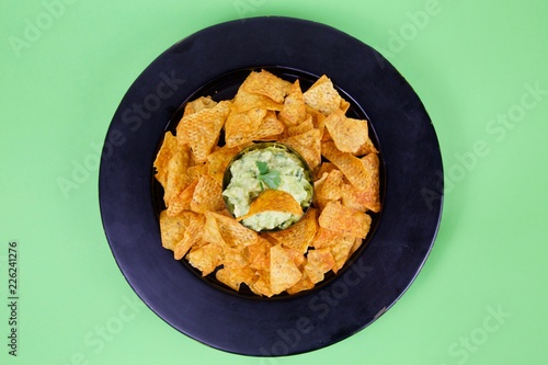 Natural fresh guacamole dip with avocado and corn chips on plate