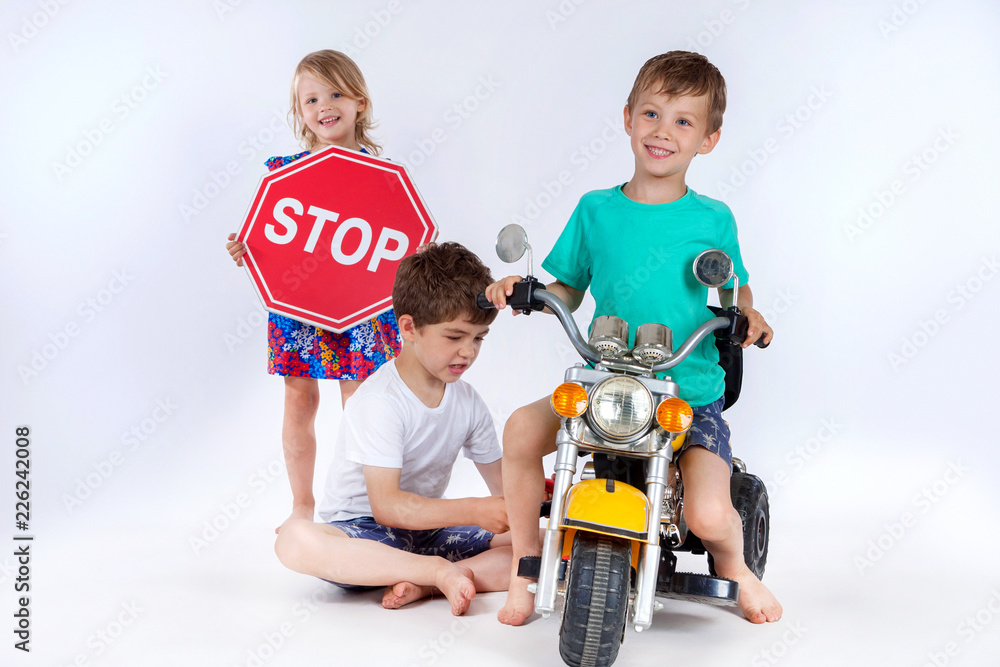Children posing studio. Boys and girls playing bikers. Children on a motorcycle. Stop sign. Little drivers. Children posing studio. Boys and girls playing bikers. Children on a motorcycle. Stop sign. Little drivers.