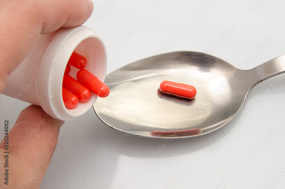 Red capsules pill spilled out of white plastic bottle. Global healthcare concept. Antibiotics drug resistance. Antimicrobial capsule pills. Pharmaceutical industry. Pharmacy. Red capsules pill spilled out of white plastic bottle. Global healthcare concept. Antibiotics drug resistance. Antimicrobial capsule pills. Pharmaceutical industry. Pharmacy.