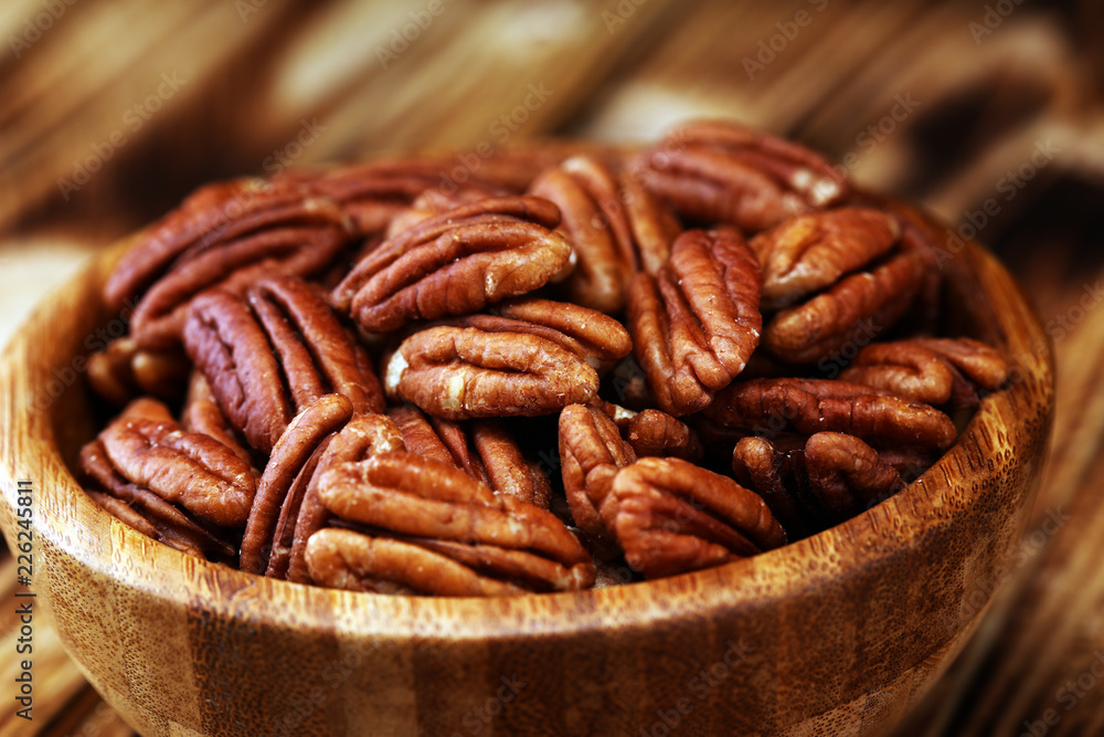 Pecan nuts on a table and pecan nuts in bowl Pecan nuts on a table and pecan nuts in bowl