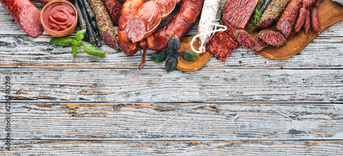 Assortment of salami and snacks. Sausage Fouet, sausages, salami, paperoni. On a white wooden background. Top view. Free space for your text.