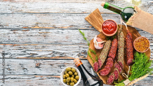 Fuete sausage, salami, paperoni on the kitchen blackboard. On a white wooden background. Top view. Free space for your text.