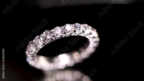 Engagement diamond ring rotating on black background, macro with shallow DoF