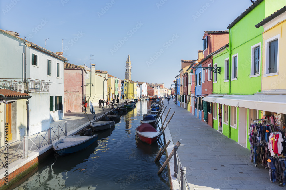 colorful rows of houses and boats of Burano island at sunny day, Venice, Italy