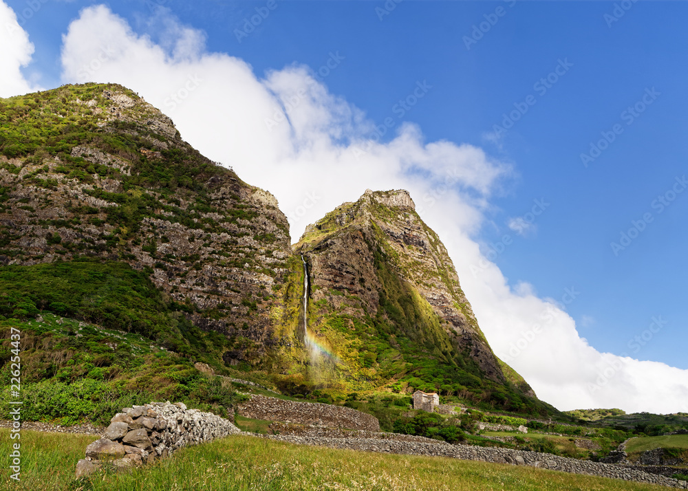Big waterfall with rainbow on the Azores island Flores, steep imposing rock face, blue sky with clouds, a landmark of the island - Location: Azores, Flores Island, Faja Grande, Ribeira das Casas