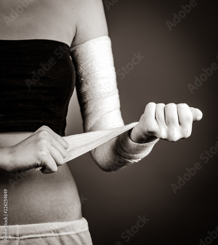 Strong girl's body with with elastic bandage on hand. Image in black and white style