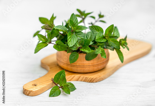 Mint in small basket on natural wooden background, peppermint, selective focus, close up