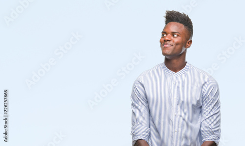 Young african american man over isolated background smiling looking side and staring away thinking.