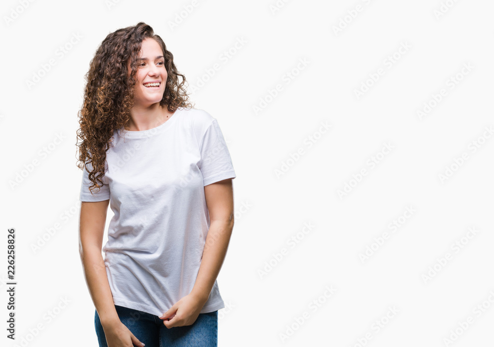 Beautiful brunette curly hair young girl wearing casual t-shirt over isolated background looking away to side with smile on face, natural expression. Laughing confident. Beautiful brunette curly hair young girl wearing casual t-shirt over isolated background looking away to side with smile on face, natural expression. Laughing confident.