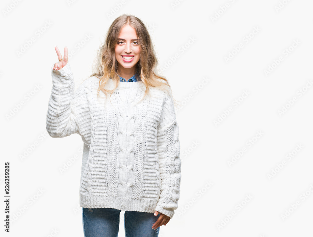 Beautiful young blonde woman wearing winter sweater over isolated background showing and pointing up with fingers number two while smiling confident and happy. Beautiful young blonde woman wearing winter sweater over isolated background showing and pointing up with fingers number two while smiling confident and happy.
