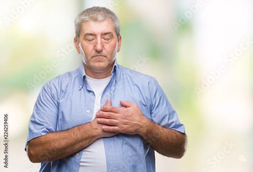 Handsome senior man over isolated background smiling with hands on chest with closed eyes and grateful gesture on face. Health concept.