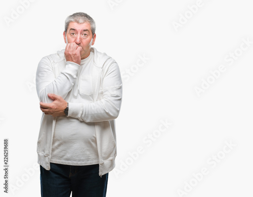 Handsome senior man wearing sport clothes over isolated background looking stressed and nervous with hands on mouth biting nails. Anxiety problem.